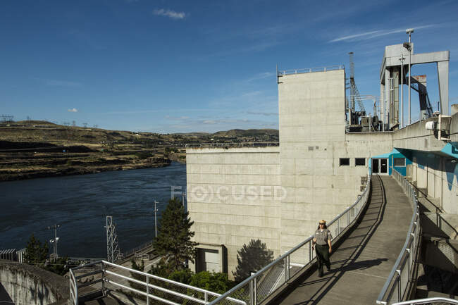A park employee walks on the Dalles Dam in The Dalles, Oregon. — Stock Photo