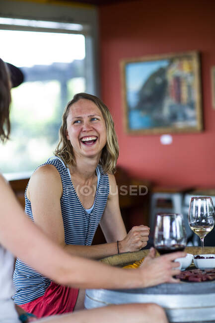 Una joven se ríe mientras disfruta del vino en una bodega en The Dalles, OR - foto de stock