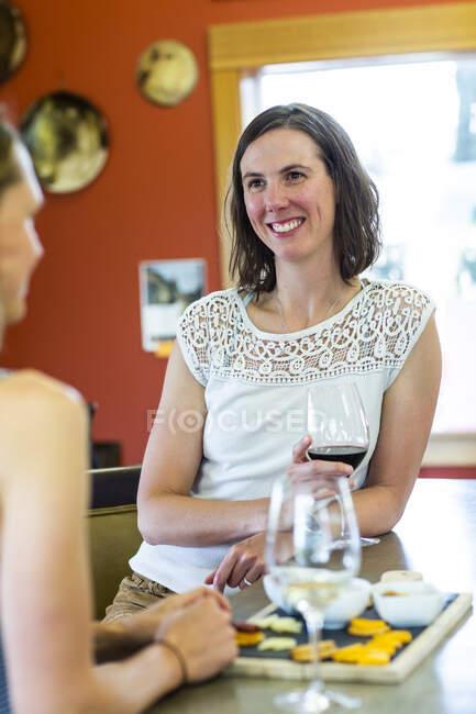 Una joven sonríe mientras disfruta del vino en una bodega en The Dalles, OR - foto de stock