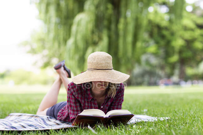 A young woman reads a book in a park in the Columbia Gorge. — Stock Photo