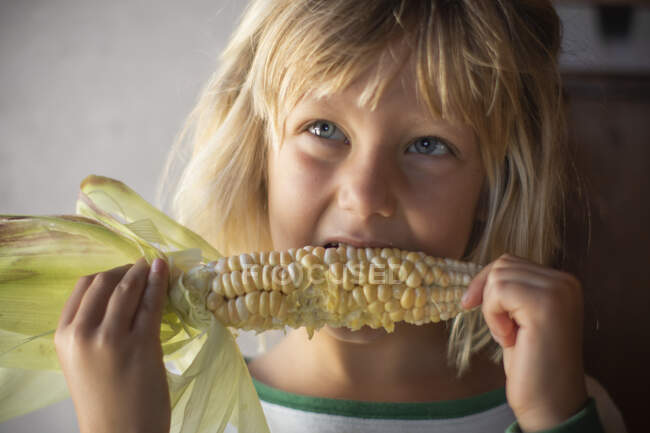 Junges Mädchen isst gelben Mais, während es nach oben schaut — Stockfoto