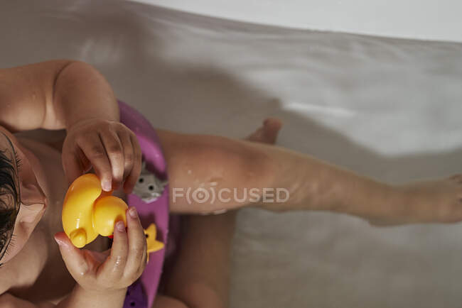 Happy baby playing with soap foam in home bathroom. Rubber duck in foam bath. — Stock Photo