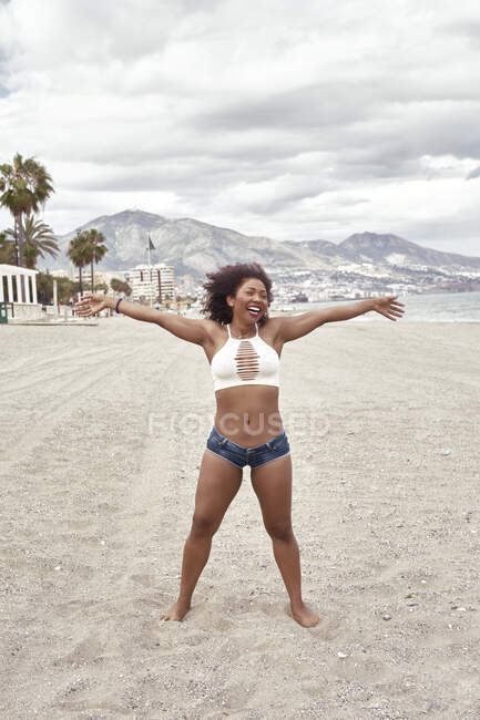 Black woman in short jeans poses spleens high on the beach — Stock Photo