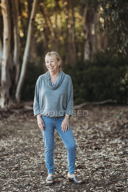 Porträt einer erwachsenen Seniorin, die im Wald lächelt — Stockfoto