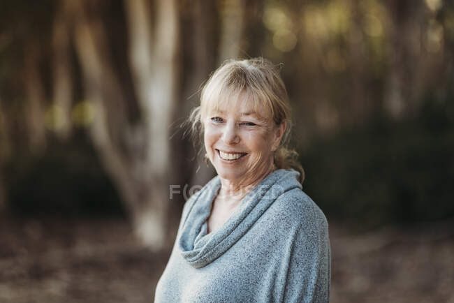 Retrato de una mujer adulta mayor sonriente sonriendo en el bosque - foto de stock