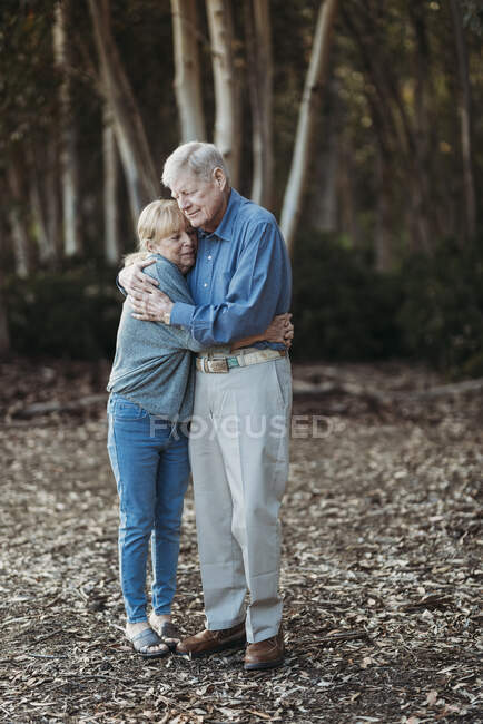 Retrato de pareja adulta jubilada mayor abrazándose en el bosque - foto de stock