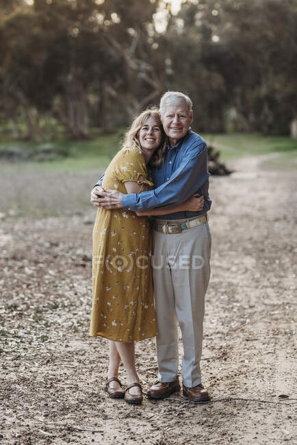 Portrait of adult woman and senior father embracing at park — Stock Photo