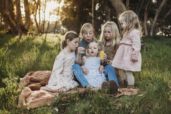 Image de style de vie de grand-mère soufflant des bulles avec les petites-filles — Photo de stock