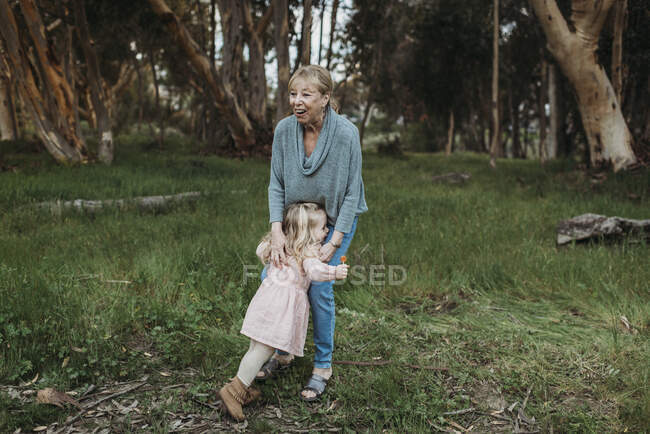 Young granddaughter running to hug grandmother in field — Stock Photo