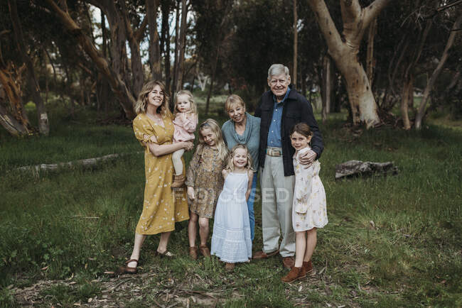 Portrait of multigenerational family smiling and embracing in field — Stock Photo