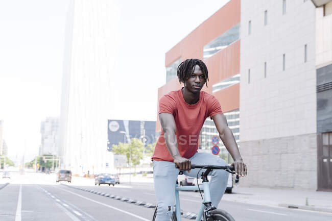Seitenansicht eines afroamerikanischen männlichen Radfahrers, der auf einer sonnigen Böschung Fahrrad fährt — Stockfoto
