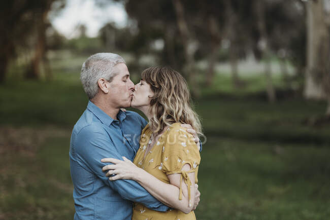 Portrait of married couple closely embracing and kissing outside — Stock Photo