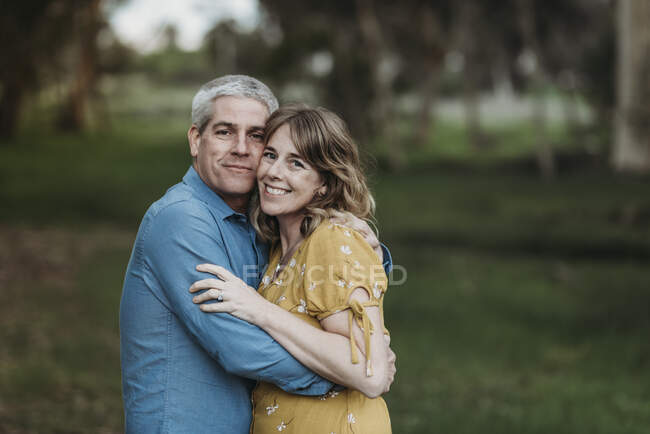 Portrait of married couple closely embracing and smiling in forest — Stock Photo