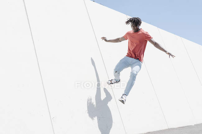 Baixo ângulo de salto masculino preto hipster ativo na rampa no parque de skate — Fotografia de Stock