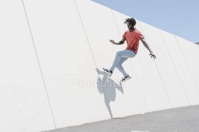 Faible angle d'hipster actif mâle noir sautant sur la rampe dans le skate park — Photo de stock