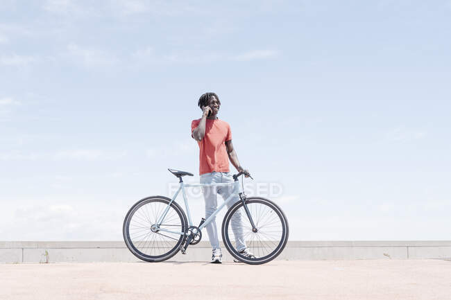 Vista lateral da bicicleta de equitação de ciclista masculino afro-americano no dique ensolarado — Fotografia de Stock