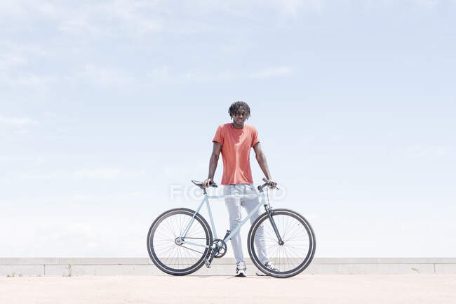Cheerful hipster African American guy with bike standing on street in sunny day — Stock Photo