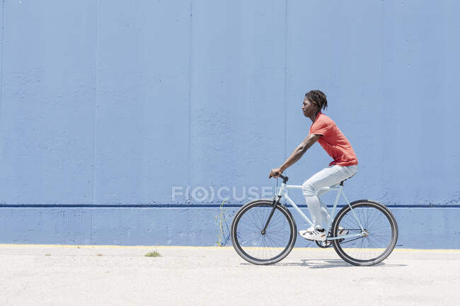 Side view of African American male cyclist riding bike on sunny embankment — Stock Photo