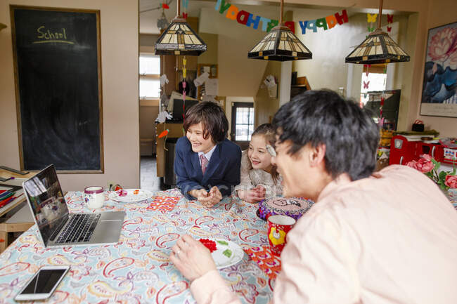 A happy family gather in front of computer for a zoom birthday party — Stock Photo