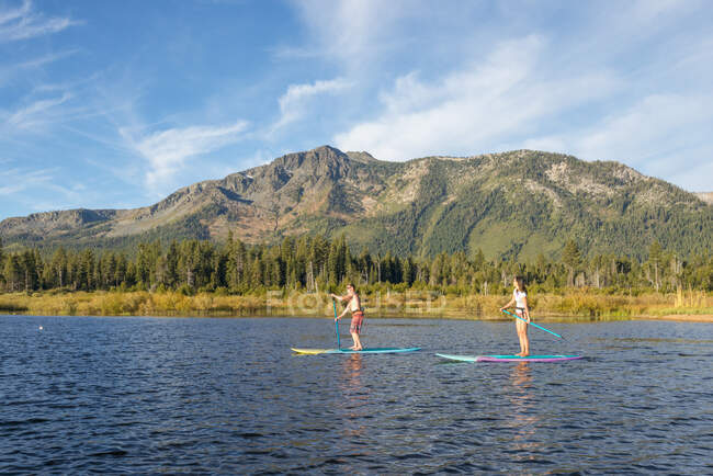 Stand up paddle boarding en el lago Tahoe junto al monte Tallac, CA - foto de stock