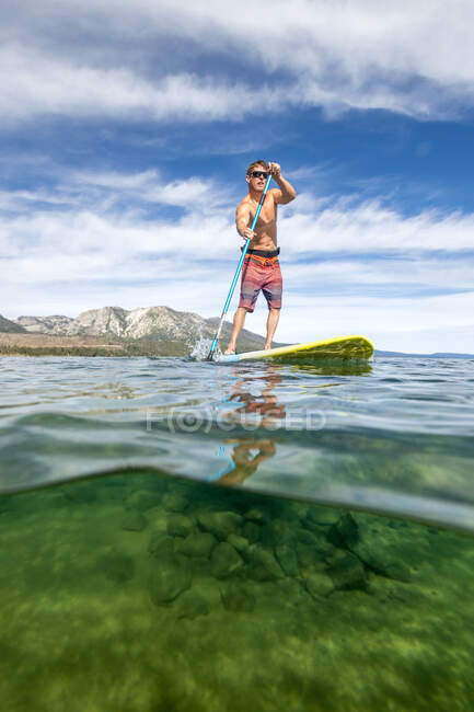 A man stand up paddle boarding on Lake Tahoe, CA — Stock Photo