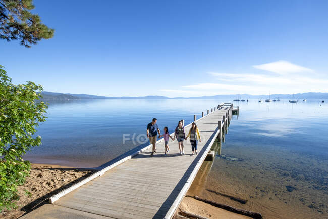 Una familia camina en un muelle en un hermoso día tranquilo en South Lake Tahoe, California. - foto de stock