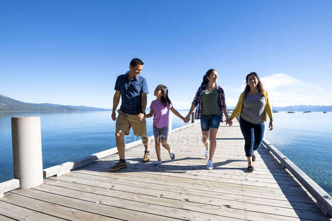 Родина посміхається і тримається за руки, ходячи по пірсу в сонячний день у Південному озері Тахо (штат Каліфорнія).. — стокове фото