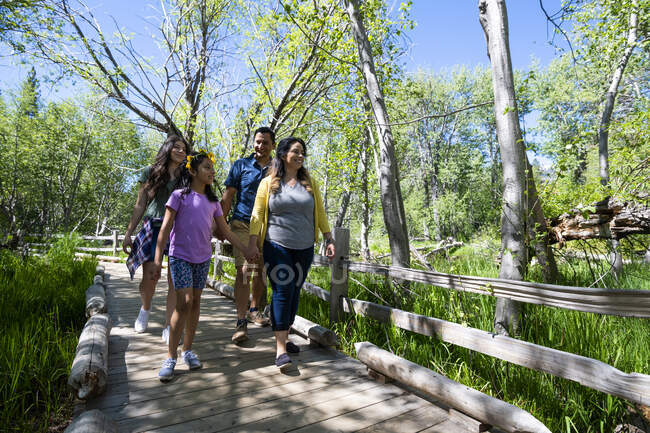 Eine Familie wandert an einem Sommertag am Taylor Creek in der Nähe des South Lake Tahoe, Kalifornien, auf einem von Bäumen und üppiger Vegetation umgebenen Holzweg. — Stockfoto