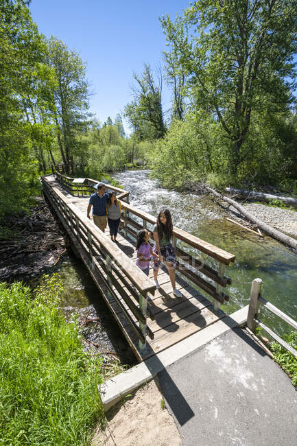 A family walks across a bridge over Taylor Creek on a summer day in South Lake Tahoe, California. — Stock Photo