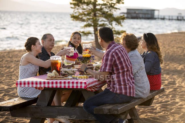 A family enjoys a picnic dinner at sunset on the shoreline of Nevada Beach in Lake Tahoe, Nevada. — Stock Photo
