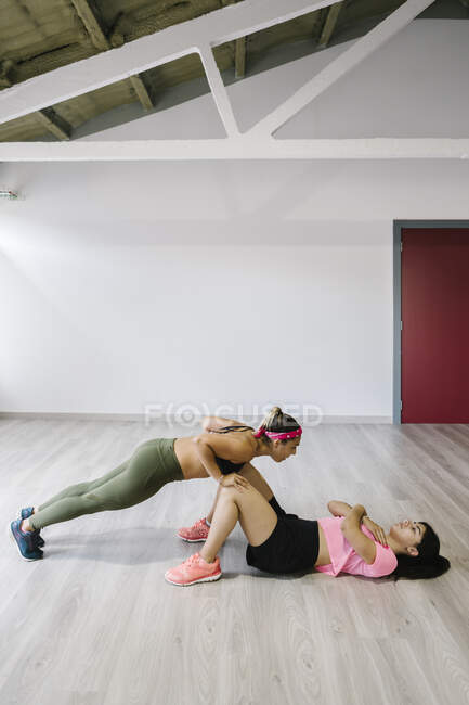 Jeune fille de formation dans la salle de gym avec son entraîneur personnel — Photo de stock