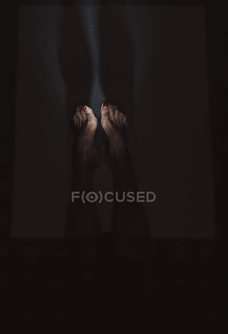Reife Frauenbeine mit rot lackierten Nägeln — Stockfoto