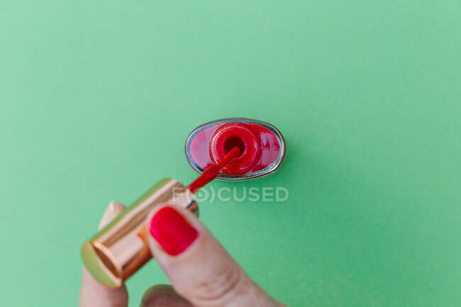 Woman hand with nail polish on color background — Stock Photo