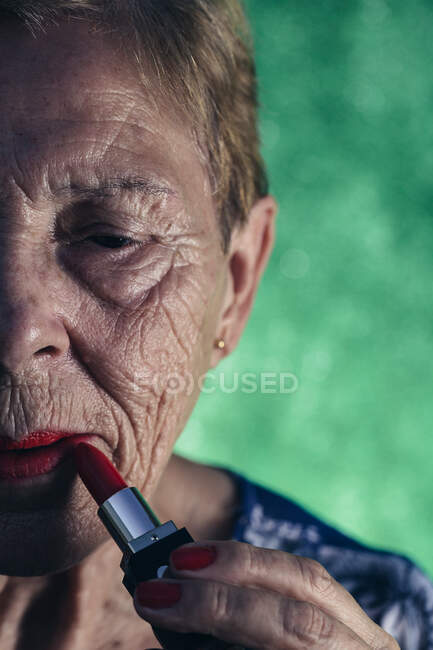 Donna matura in primo piano dipingendo le labbra in rosso — Foto stock