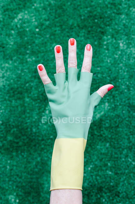 Main avec un gant en caoutchouc sur fond vert — Photo de stock