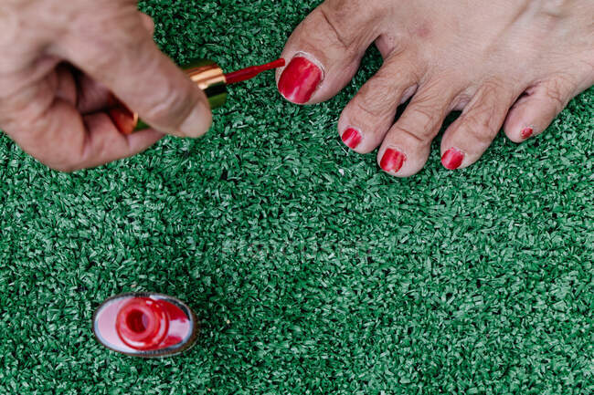 Vecchio che dipinge le unghie dei piedi di sua moglie rosse viste dall'alto — Foto stock