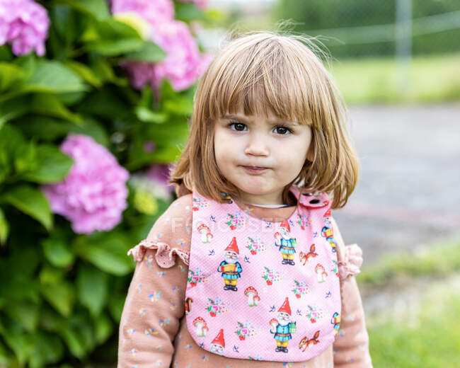 Girl with serious gesture and pink bib looks at the camera — Stock Photo