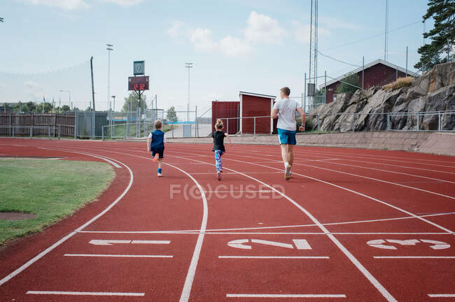 Батько біжить зі своїми дітьми на гоночній трасі — стокове фото
