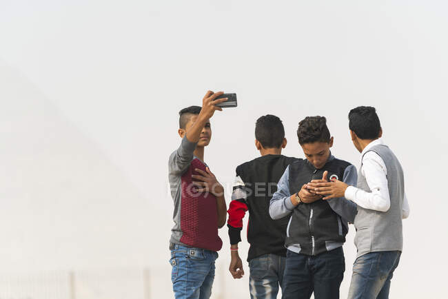 A group of Egyptian boys outside on their phones — Stock Photo