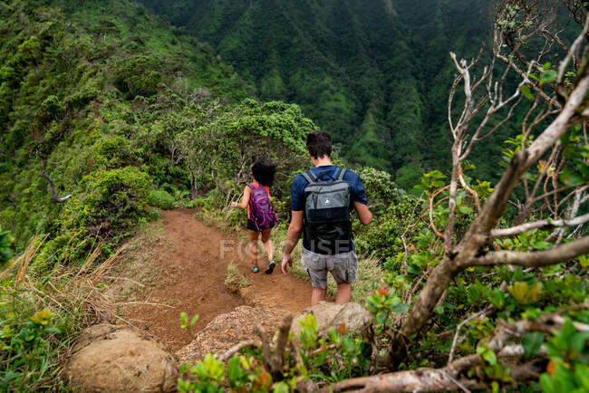 Dos adultos caminando por una línea de cresta en Oahu, Hawái - foto de stock