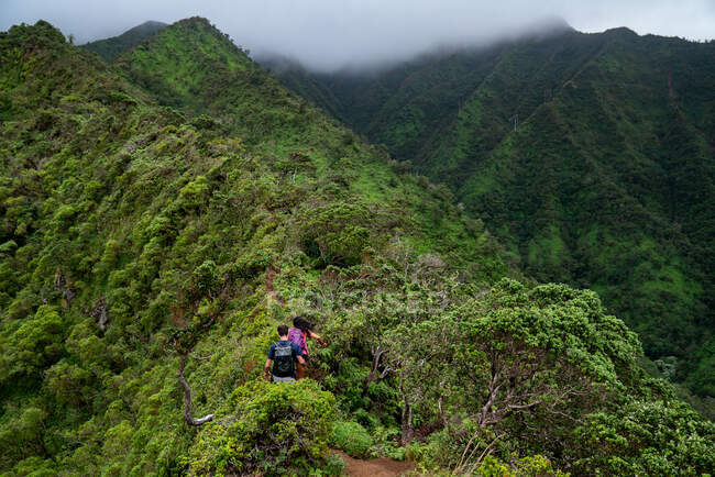 A couple hikes a ridge line on a cloudy day in Oahu, Hawaii — Stock Photo