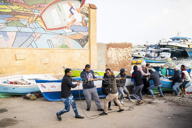 Eine Gruppe Männer zieht ein Boot an Land — Stockfoto