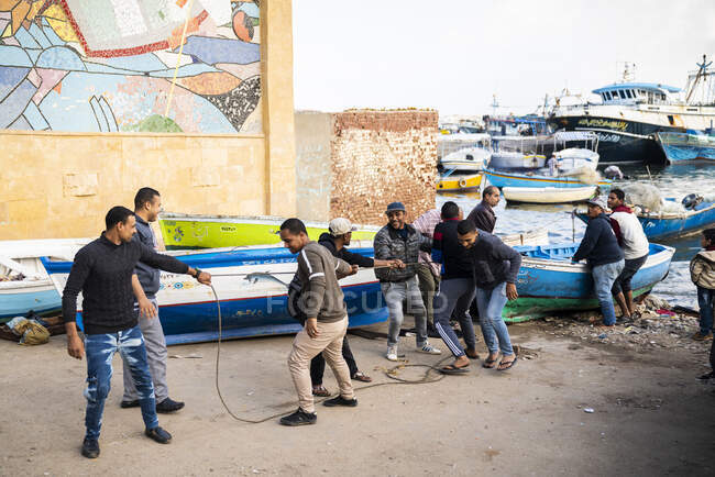 A group of men work to pull a boat on shore — Stock Photo