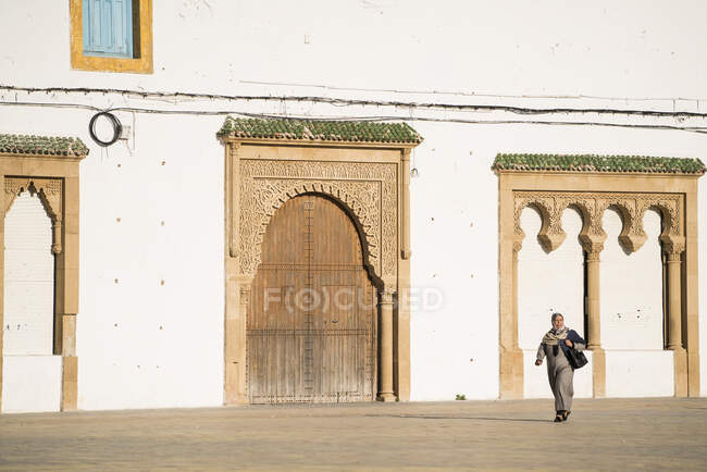 Femme marchant par mur de forteresse marocaine — Photo de stock