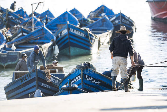 Pescadores marroquíes trabajando para traer barcos a la costa - foto de stock