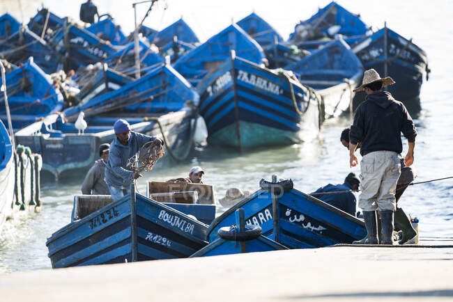 Fishermen bringing blue boats onto pier — Stock Photo