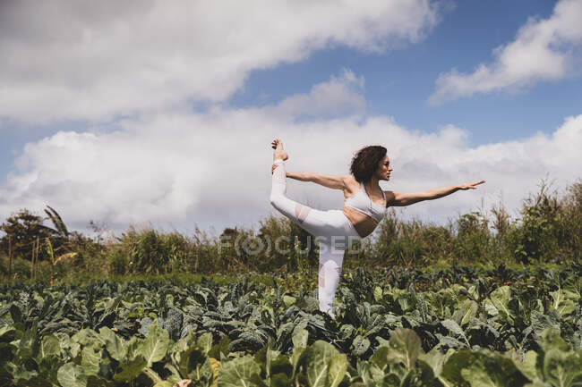 Женский йог в детской позе в поле зеленых овощей — стоковое фото