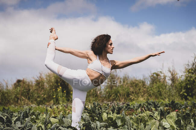 Femme forte dans la pose de danseuse tout en pratiquant le yoga — Photo de stock