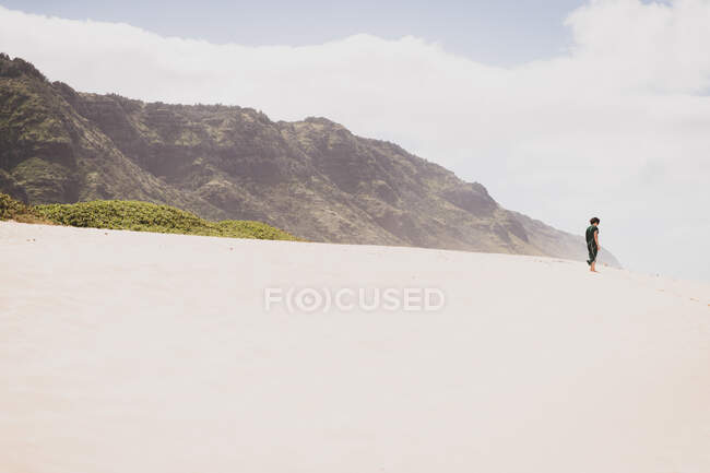Femme se tient seule sur une colline de sable en face d'une montagne — Photo de stock