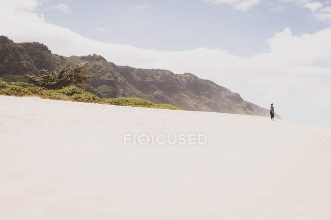 Woman stands on a sandy hill in front of a mountain in the distance — Stock Photo